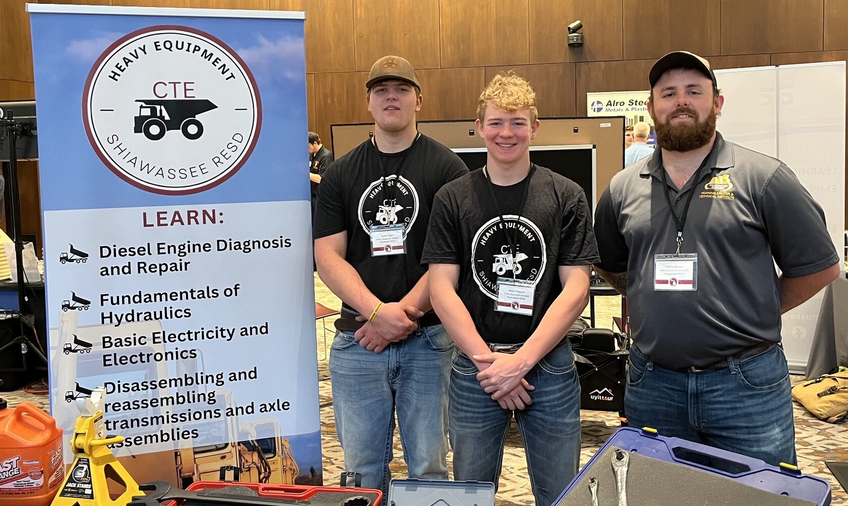 Instructor Sayles, Noah Kiger, and Nolan Rogalla at the CTE Showcase in Lansing